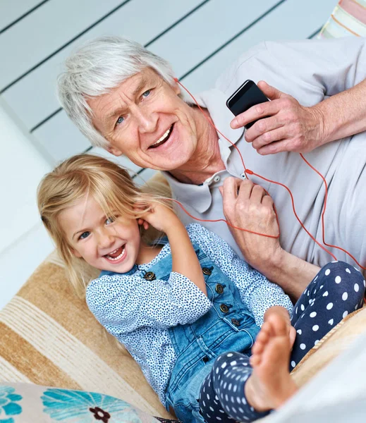 Finding common ground in music. an adorable little girl listening to music from a cellphone with her grandfather