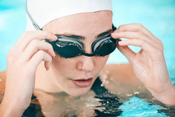Swimmer, hands and face with goggles in fitness sports for exercise, workout or training in swimming pool. Sporty athletic woman professional in practice for underwater swim competition in swimwear.