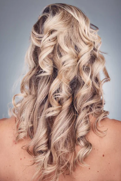 Curly hair, wellness and woman with healthy hairstyle texture after salon treatment in a studio. Gray background, isolated and model with hairdresser balayage, dye and growth from haircut and keratin.