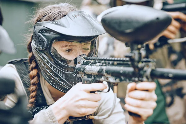 Paintball, gun and woman with helmet aim for shooting ready for game, arena match and battlefield. Extreme sports, military adventure and girl with weapon in camouflage, action and safety gear.