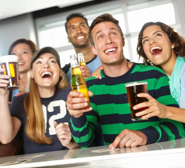 Epic, exciting game. A group of friends cheering on their favourite team at the bar