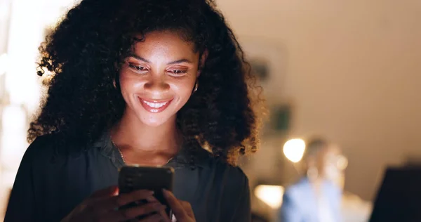 Social media, phone and happy woman typing on a dating app or website for a love connection and romance. Smile, relaxed and young woman texting, chatting and online dating in a dark night at home.