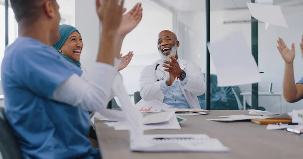 Doctors, applause and high five with success and paper confetti, celebrate win in health and cheers for team building. Happy, medical innovation win and target goal with motivation and diversity