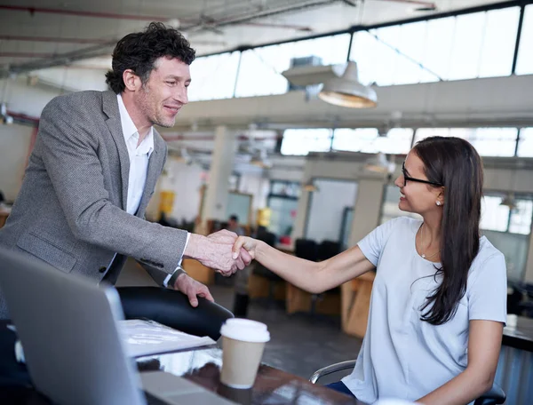 You are perfect for the job. two coworkers shaking hands in an office