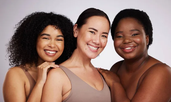 Portrait, diversity and women with skincare, smile and bonding together on grey studio background. Face, multiracial and females with cosmetics, support or solidarity with body positivity on backdrop.