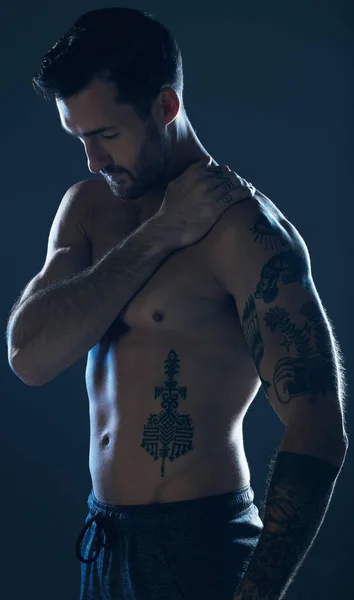 Fitness, studio and man with tattoo, muscle and strong body for wellness, exercise and training. Motivation, sexy model and body of male athlete on dark background for workout, power and bodybuilder.