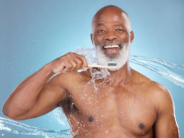 Portrait, water splash and black man with toothbrush, toothpaste or dental hygiene for wellness, brushing and blue studio background. Senior African American male, guy and clean teeth for oral health.