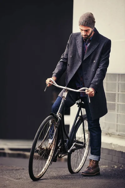 Dressing well is a form of good manners. a handsome young man in winter wear standing with his bicycle