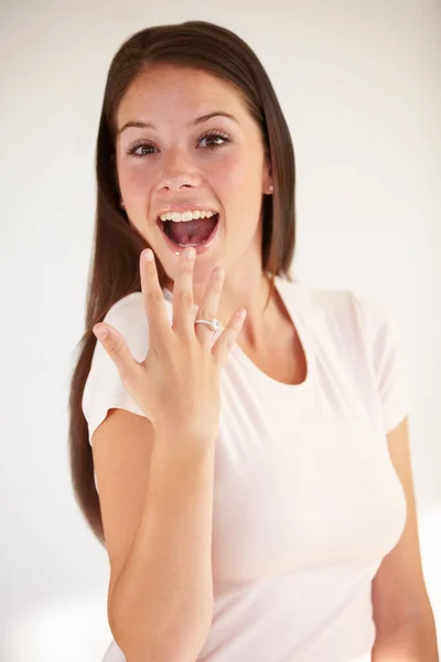 Portrait of woman excited with ring for engagement, marriage and wedding on white background. Love, wow and happy girl show diamond jewellery on hand for romance celebration, commitment and proposal.