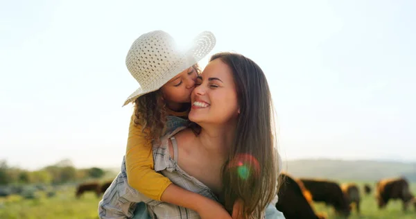 Mother, child on farm, hug and bonding in the countryside, together farming, mom piggy back kid with fun outdoor in nature. Happy, woman and girl, agriculture and field, sustainability and cattle