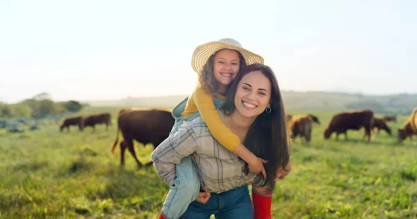 Family, farm and fun with a girl and mother playing on a grass meadow or field with cattle in the background. Agriculture, sustainability and love with a woman and her daughter enjoying time together.