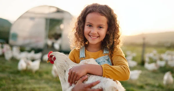 Chicken, smile and girl on a farm learning about agriculture in the countryside of Argentina. Happy, young and sustainable child with an animal, bird or rooster on a field in nature for farming.