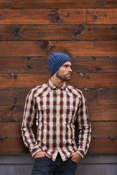 Street style. a handsome young man in trendy winter attire against a wooden background