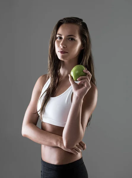 Got to keep the energy up. Attractive young woman taking a break from her workout to eat an apple