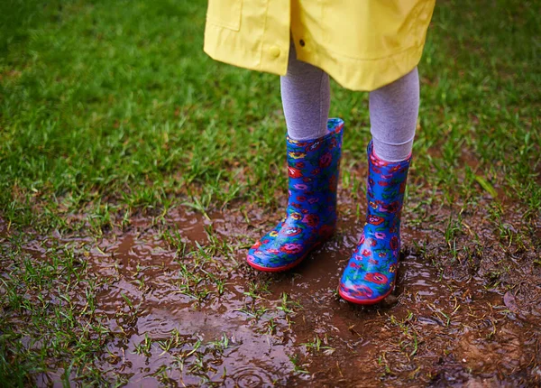 Mind the mud. a child playing in the rain outside