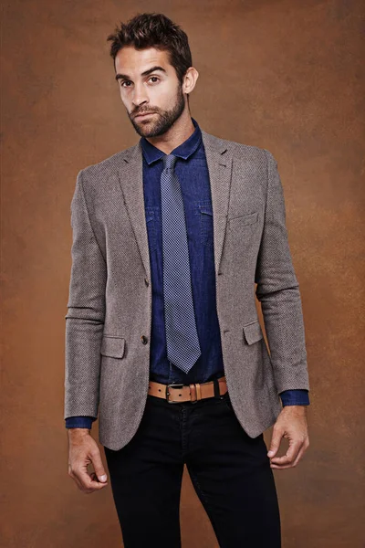 Being well-dressed has nothing to do with fashion...a stylishly dressed young man posing against a brown background