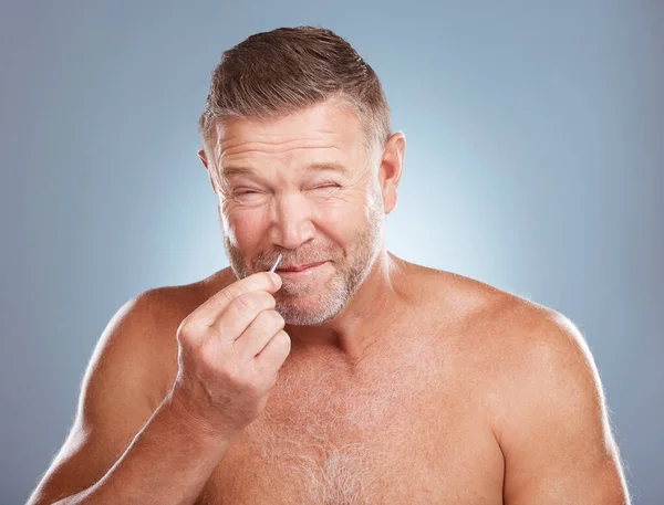 Tweezer, grooming and man in a studio for a hair removal, skincare and cosmetic face routine. Self care, epilation and mature male model doing facial plucking for hygiene treatment by gray background.