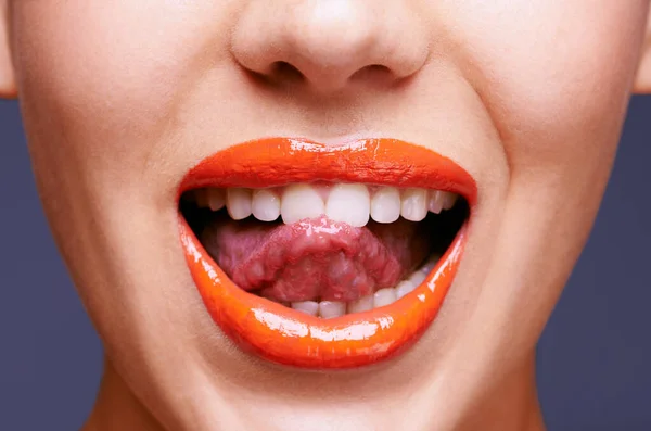 Add some color to your day. a woman sticking out her tongue with her lips covered in orange lipstick