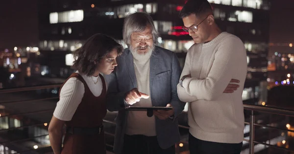 Business team, tablet and night on city building rooftop talking global networking, digital marketing and social media. Man and woman with 5g network on mobile stock market app for innovation idea.