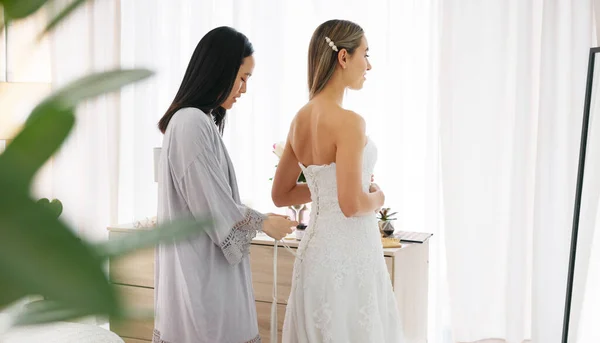 Happy bride in wedding dress, friends helping with knot on luxury corset back string and young women together in home. Asian woman supporting hug, marriage ready preparation and bridesmaid happiness.