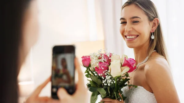 Bride, bridesmaid and wedding picture with phone with flowers or bouquet, fashion dress and an excited smile for social media. Happy woman and friend with mobile smartphone before a marriage ceremony.