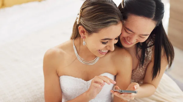 Friends, bride and bridesmaid smartphone selfie smile together for fun wedding photograph memory. Happy, joyful and cute women friendship with asian and caucasian woman looking at bridal pictures