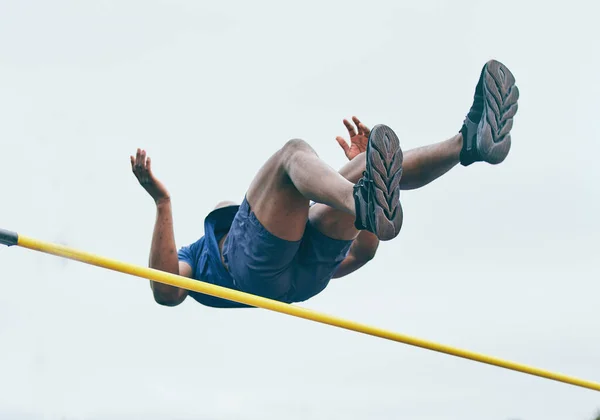 Fitness, athletics high jump by man at a stadium for training, energy and cardio against sky background. Jumping, athlete and male outdoors for performance, endurance and competition on mock up.
