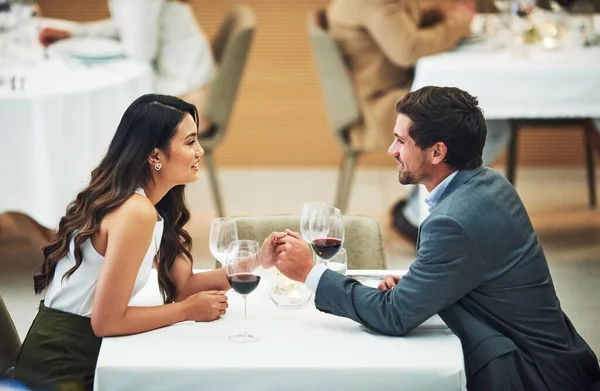 Restaurant, date and couple holding hands with wine for romantic dinner, relax and anniversary celebration. Relationship, fine dining and man and woman enjoying luxury drinks, alcohol and valentines.