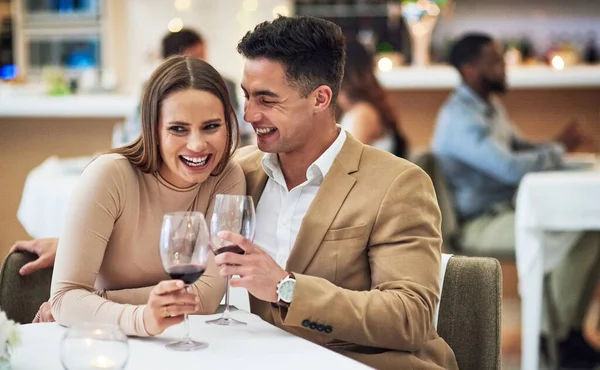 Love, wine and happy couple at a restaurant for valentines day, celebration and bonding while laughing. Alcohol, fine dining and woman with funny man on first date, anniversary or birthday dinner.
