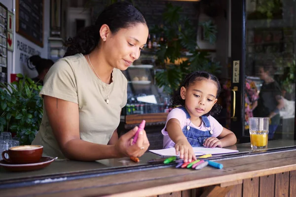 Cafe, family mother and child learning, drawing or color education with support, help and fun at restaurant. Woman or mom with girl kid writing in coffee shop for creativity, teaching and activity.