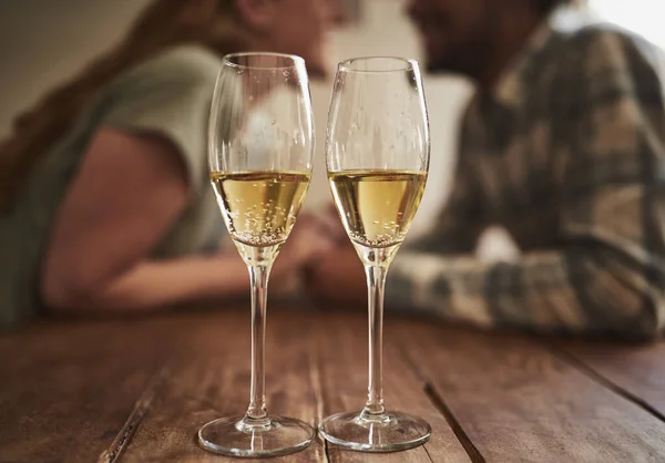 Champagne, glass and love on valentines day with a couple kissing in the background of a restaurant for romance. Alcohol, drink or dating with a man and woman sharing a kiss on a romantic date.