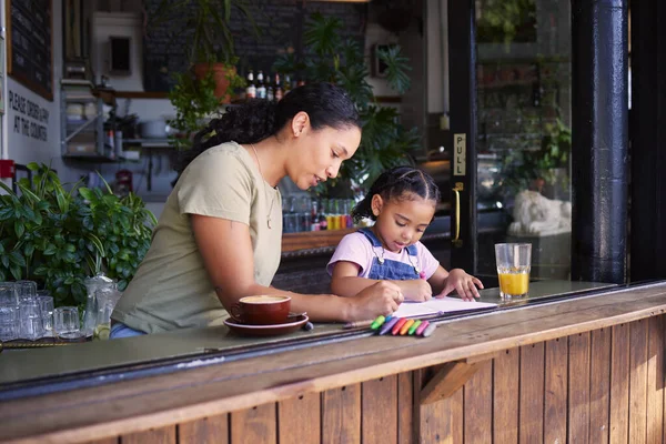 Coffee shop, black family and crayons with a mother and daughter coloring a book at a cafe window together. Art, creative and love with a woman and happy female child bonding in a restaurant.
