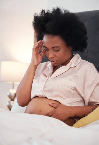 Pregnant, headache and black woman with depression, bedroom and stress with cramps, frustrated and healthcare. Pregnancy, African American female and lady with anxiety, mental health and discomfort.