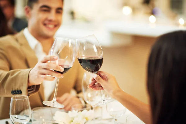 Toast, wine and couple in restaurant for celebration, romantic dinner and anniversary together. Relationship, fine dining and man and woman cheers with drinks, alcohol and relax at hotel on honeymoon.