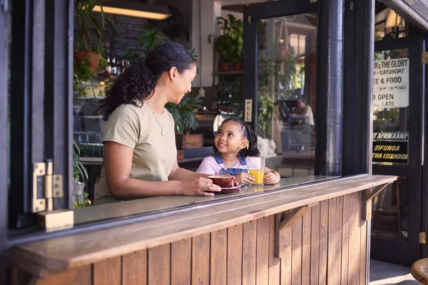 Coffee shop, black family and children with a mother and daughter enjoying a beverage in a cafe together. Juice, caffeine and kids with a woman and happy female child bonding in a restaurant.