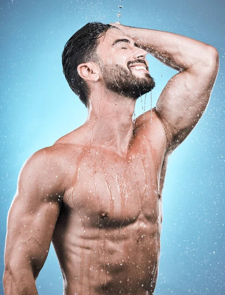 Body, man and water for cleaning, morning routine and grooming against a blue studio background. Skincare, male and gentleman with cosmetics, wet and drops for hygiene, beauty or wellness on backdrop.