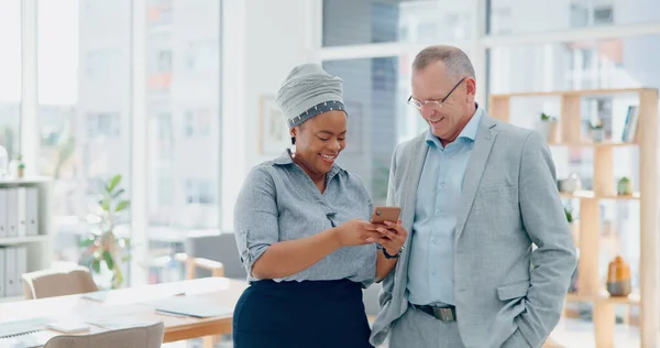 Business, office staff and phone of a black woman showing mobile social media review to senior boss. Corporate, company employee and mobile phone of a digital marketing manager with elderly ceo.