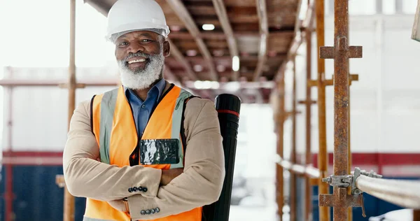 Building engineer, architect and construction worker with a black man standing arms crossed with a positive mindset, motivation and vision on scaffold. Portrait of mature male contractor with a smile.