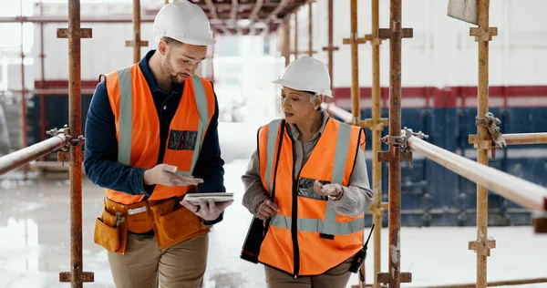 Construction worker, working together and conversation with tablet, communication and construction business. Engineer, job site with man and woman talking, collaboration and building trade