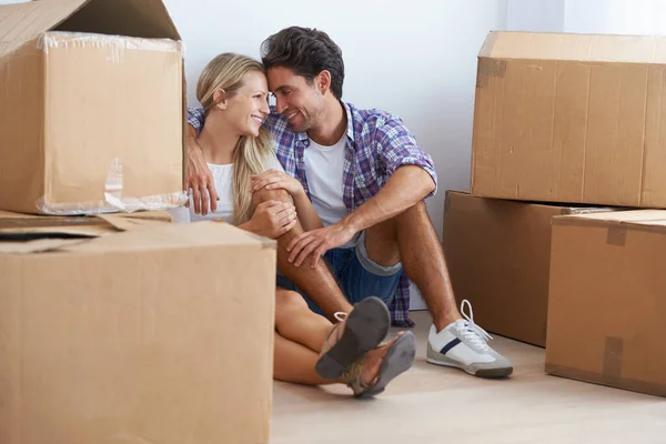 Creating a life together. A happy young couple cuddling while sitting on the floor in their new home and surrounded by boxes