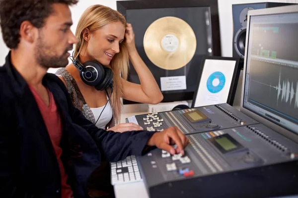 High resolution recording. A young audio engineer working on a mixing desk with his blonde colleague sitting next to him