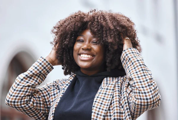 Black woman, portrait smile and afro hairstyle for fashion in city travel, trip or outdoor journey. Happy African American female touching stylish curls and smiling in happiness for traveling in town.