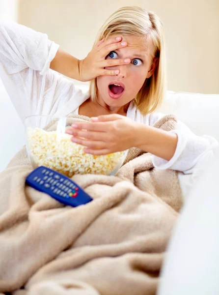 Horror movies are exciting. A young woman looking scared while watching a movie
