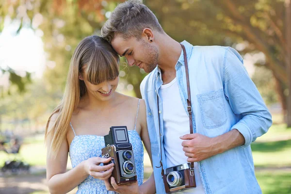 Sharing love and a passion for photography. a young couple taking pictures outside with vintage cameras