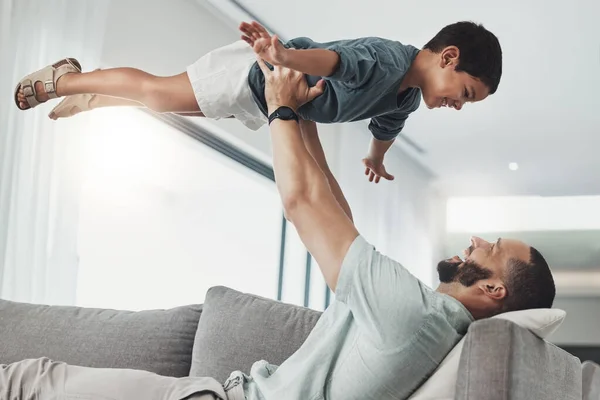 Relax, smile and lifting with father and son on sofa of living room for bonding, playful and support. Wellness, game and strong with dad and child in family home for care, quality time and happy.