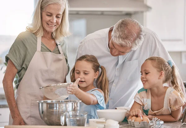 Family, baking and children helping grandparents in their home kitchen. Senior woman, man and girl kids learning about food, cooking or dessert recipe with love, care and quality time for development.