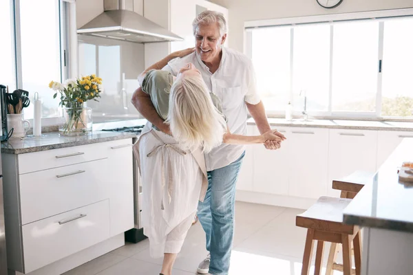 Senior couple dancing, kitchen and happiness with love, care and support in morning at house. Elderly man, old woman and dance together with smile, hands and support in retirement in home with trust.