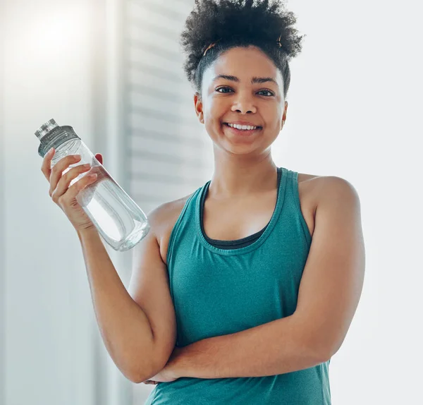 Water, bottle, black woman portrait and of a athlete in a gym after workout and sport. Hydration, drink and healthy young person in a wellness and health center with bottle for training and exercise.