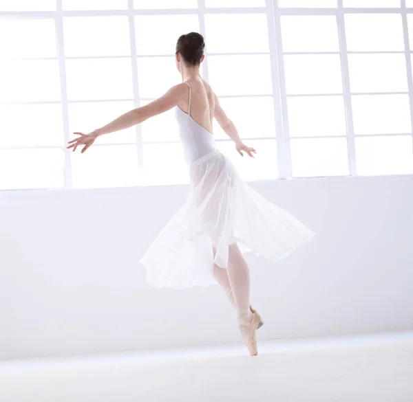 Living art. Graceful young ballerina in white dancing en pointe