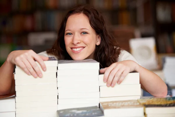 Ill take them all, thank you. Portrait of a young woman leaning over stacks of books